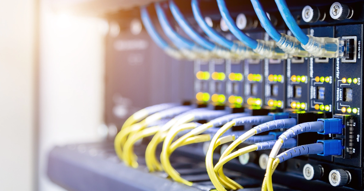 Network switch with blue and yellow cables and flashing green and yellow lights.