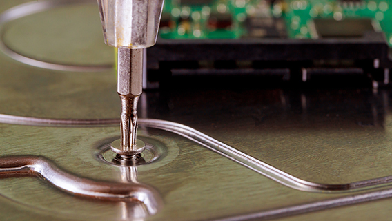 Macro shot of a screwdriver unscrewing a screw from a hard drive enclosure.