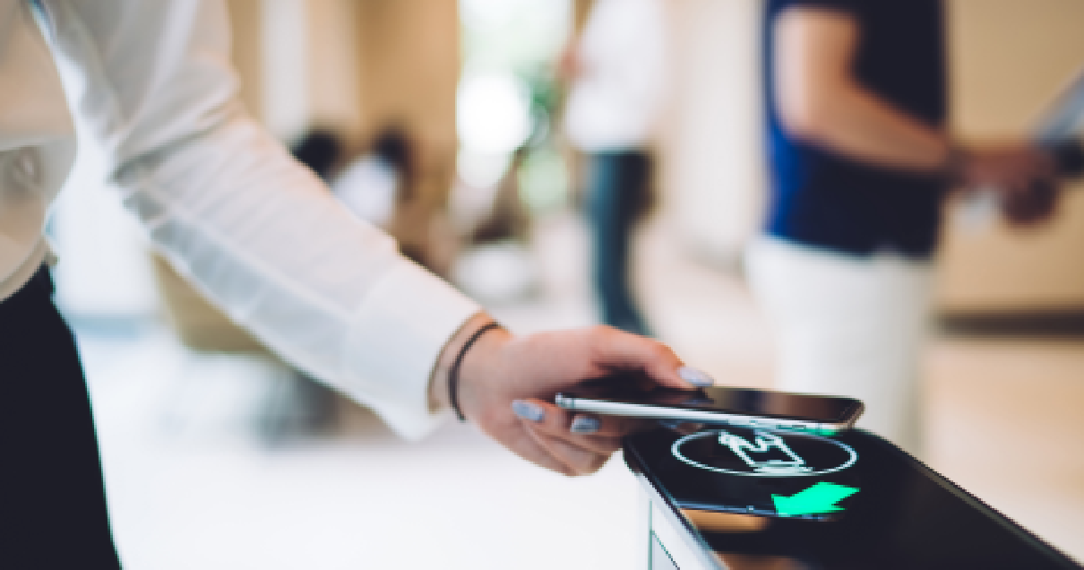 Le bras d'une femme tenant un téléphone alors qu'il passe devant un scanner à une sorte de point de contrôle d'accès.