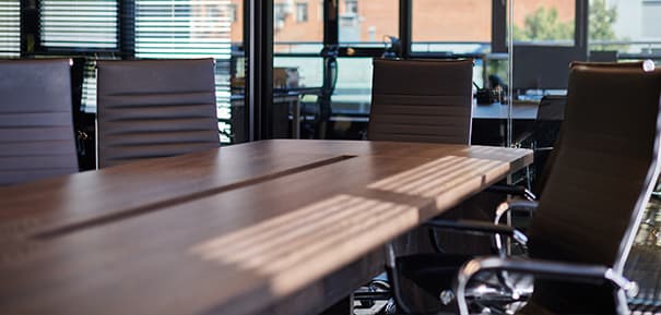 Fancy wood boardroom meeting table surrounded by brown leather swivel-chairs