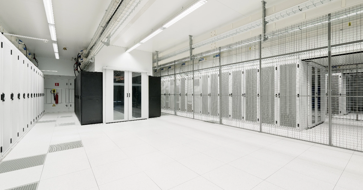 Un centre de données blanc cristal avec beaucoup d'espace ouvert et des racks de serveurs derrière des cages fermées.