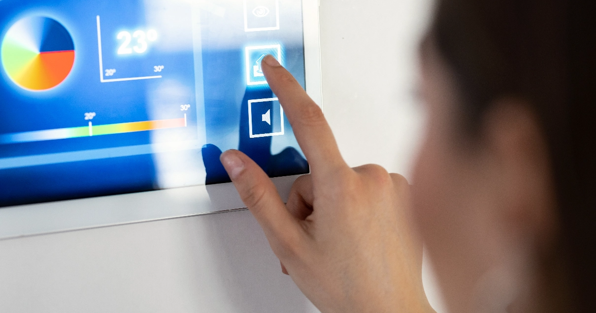 Une femme utilise l'écran tactile d'un appareil intelligent fixé au mur.
